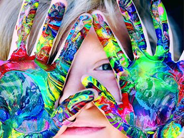 Barn med håndmaling på fingrene