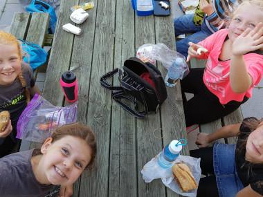 Elever samlet omkring en bænk, med madpakker